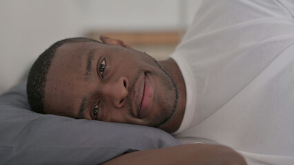 Smiling African Man Laying in Bed Awake Thinking