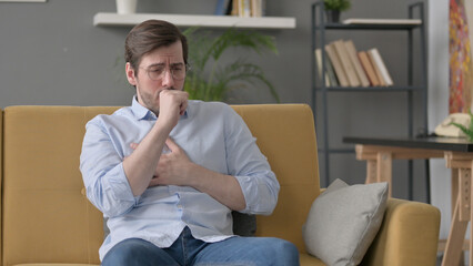 Young Man Coughing while Sitting on Sofa