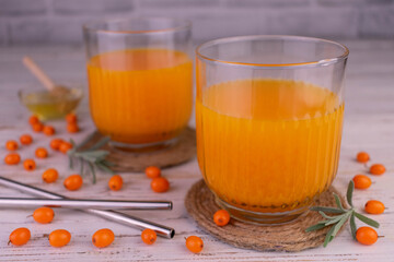 Vitamin sea buckthorn juice in glasses on a white wooden background.
