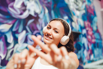 the girl makes a hashtag with her hands. a young woman wearing headphones shows a hashtag against...