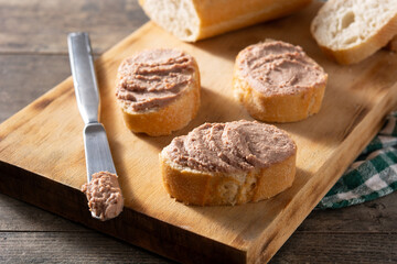 Dipping toasted bread with pork liver pate on wooden table