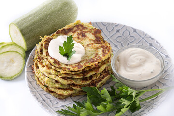 Zucchini fritters with yogurt sauce isolated on white background