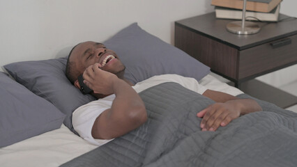 Fototapeta premium African Man Talking on Smartphone while Sleeping in Bed, Close up
