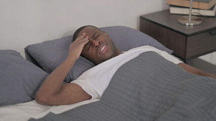 Fototapeta na wymiar African Man having Headache while Sleeping in Bed