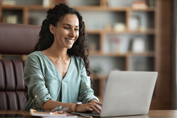 Positive young woman freelancer using laptop at home