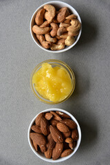 Delicious cashew nuts walnuts and hazelnuts with honey on a gray background. Delicious nuts in ceramic saucers and honey.