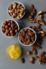 Delicious cashew nuts walnuts and hazelnuts with honey on a gray background. Delicious nuts in ceramic saucers and honey.