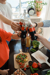 Portrait of four friends celebrating event drinking cola and eating home made pizza.