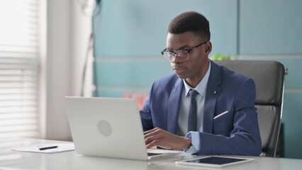 Fototapeta na wymiar Young African Businessman Working on Laptop in Office