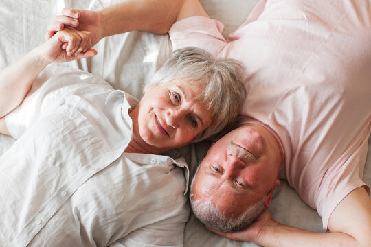 Happy elderly couple wakes up in bed in the morning
