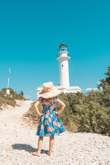 Young kid during summertime holidays looking at beautiful seascape and holding seagull feather,...