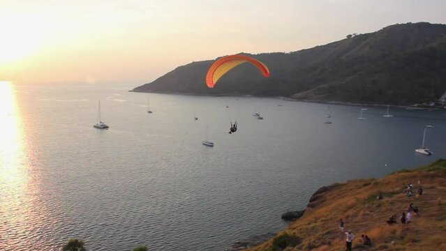 Anonymous person silhouette paragliding at splendid sunset by the sea in Phuket island, Thailand. Extreme sport activity outdoors, adventure experience concepts