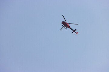 red rescue helicopter flying above in blue sky