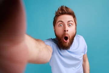 Portrait of shocked surprised handsome young adult bearded man standing with widely open mouth,...