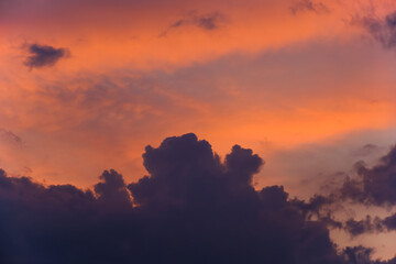 Dark clouds against a scarlet pink sky during sunset.