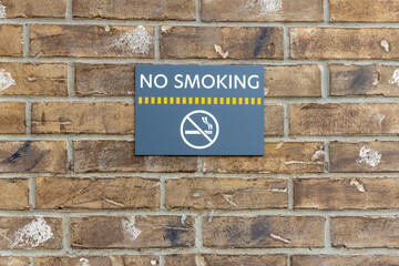 Obraz premium No smoking sign on the building, warning sign on the brick wall background, information about ban of smoking.
