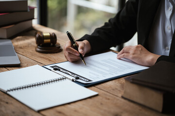 Close up of business's hand signing on agreement paperwork for selling and loan financial house properties.