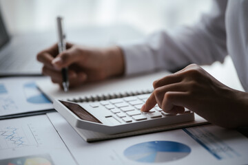 Close up of business hands working and calculating on financial and accounting graft and chart in office space.