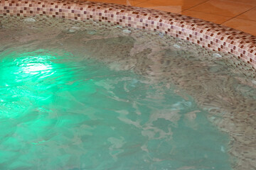Jacuzzi bath with hot water and a jet of water with bubbles with a green backlight