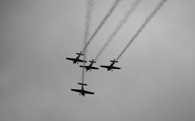 Black and white concept photo for an aerobatic show against a cloudy sky. Extreme aviation industry.