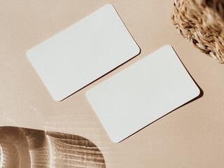 Two blank white cards, basket and glass of water on beige background top view.