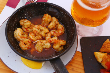 fried shrimps with lemon slice, garlic sauce aioli and tomato ketchup frying pan close up photo with beer