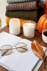 High angle view opened blank book for mockup design with sweaters and candles