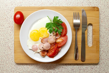 Fried eggs with fried vegetables, sausages and herbs