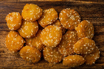 Crispy cheese nuggets served on wooden board, on dark wooden backdrop, close-up shot