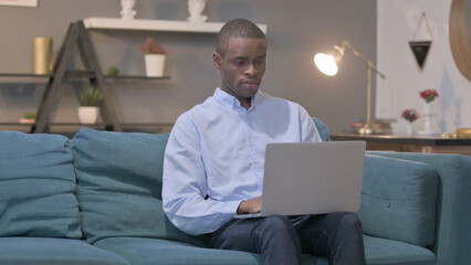 African Man Working on Laptop on Sofa