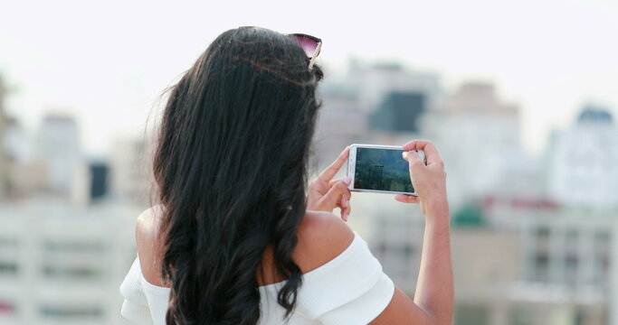 Black Girl taking photo with smartphone of city landscape. Young woman holding cellphone filming