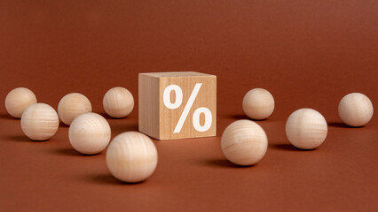 percent sign on wooden cubes against broun background with wooden balls. concept of sale and discount