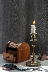 Candelabra with candle, inlaid jewelry box, women's mirror.A burning candle in a candelabra is the central composition of the still life.