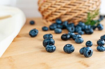 Fresh blueberries scattered on a wooden surface. Wicker basket. selective focus