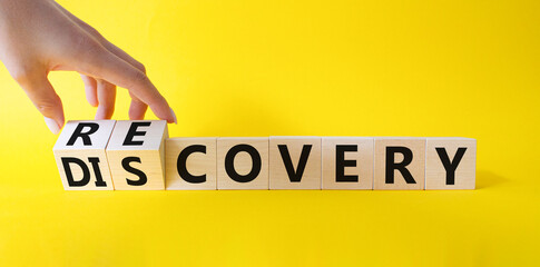 Recovery and Discovery. Businessman hand Turnes wooden cubes and changes word Discovery to Recovery. Beautiful yellow background. Business concept. Copy space