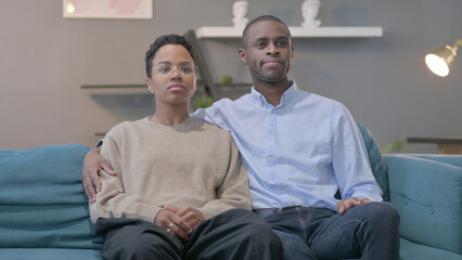 Obraz premium African Couple Looking Around While Sitting on Sofa