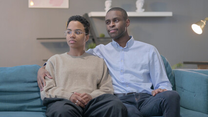 Obraz premium Couple Looking Around While Sitting on Sofa