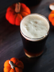 Craft autumn beer. Pumpkin ale in a glass . Small knitted pumpkins