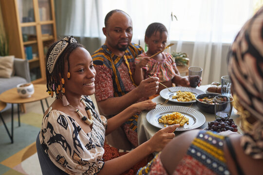 African happy girl talking to her family during holiday dinner at table at home