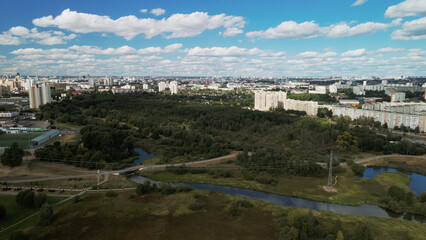 Fototapeta premium City with high-rise buildings. Park area in the foreground. Blue sky with clouds. Aerial photography.