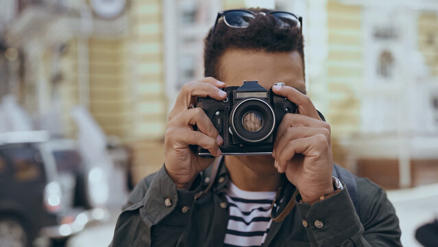 Bi-racial tourist taking photo on film camera outdoors.