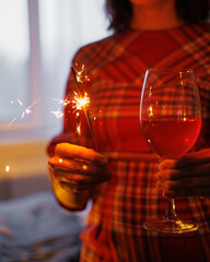 soft selective focus. woman with sparklers in her hands celebrates New Year or Christmas at home. a happy woman drinks wine with friends on her birthday and anniversary. Christmas lights and a