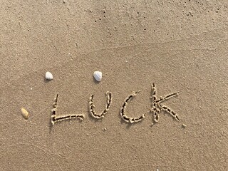 on the beach is carved with letters in the smooth sand the writing Luck