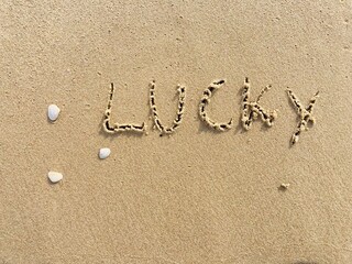 Fototapeta na wymiar on the beach is carved with letters in the smooth sand the writing Lucky