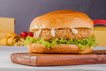 Crispy juicy Chicken Burger Meal isolated on wooden board side view on grey background fastfood