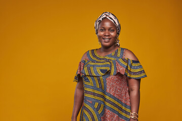 Portrait of African woman in national costume smiling at camera isolated on yellow background