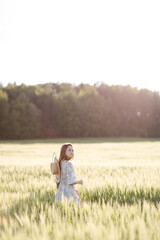 Naklejka na ściany i meble Trendy girl in stylish summer dress feeling free in the field in sunshine. High quality photo