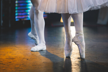 Ballet dancers couple during performance repetition, classic ballet rehearsal practicing in ballroom, view of legs in pointe shoes, ballerina and ballet dancer on a concert hall theatre stage