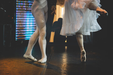 Ballet dancers couple during performance repetition, classic ballet rehearsal practicing in ballroom, view of legs in pointe shoes, ballerina and ballet dancer on a concert hall theatre stage © tsuguliev