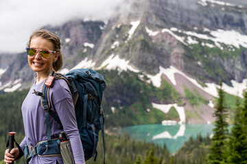 Woman hiker takes a moment to enjoy the scenery along the Grinnell Glacier Hike in Glacier National Park Montana